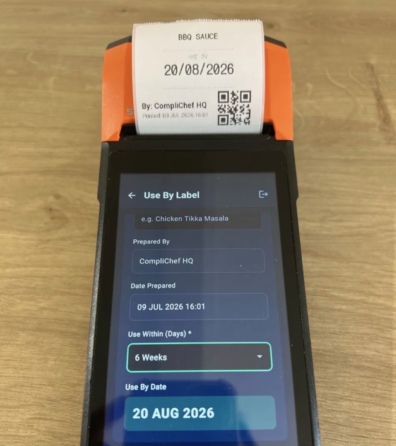 A managed Sunmi label printer printing a real CompliChef use-by label, straight from a working kitchen